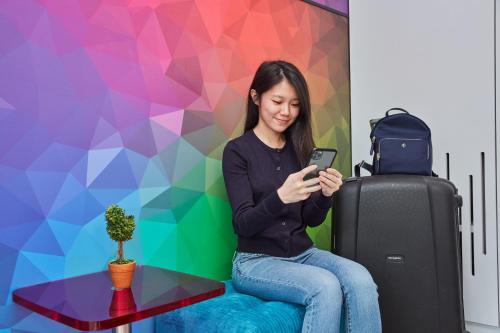 a woman sitting next to a table with a cell phone at ibis budget Singapore Ametrine in Singapore