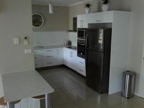 a kitchen with a black refrigerator and white cabinets at Reef Terraces on St Crispins in Port Douglas