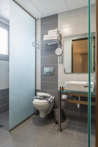 a bathroom with a toilet and a sink and a mirror at Royal Bay Suites in Kefalos