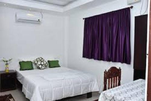a bedroom with two beds and a purple curtain at Sushils Bed and Breakfast in Port Blair