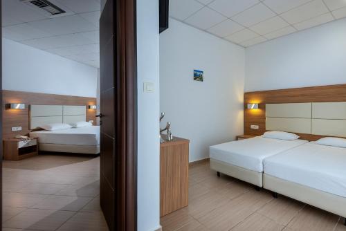 a hotel room with two beds and a mirror at Royal Bay Suites in Kefalos