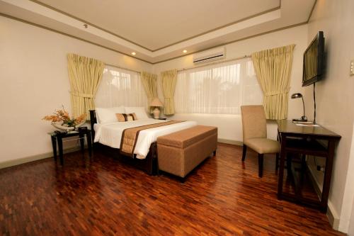 um quarto com uma cama, uma secretária e uma cadeira em Casa Pura Inn and Suites em Manila