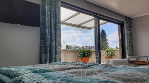 een slaapkamer met een bed en een groot raam bij Appartement mit Weitblick in Mönchengladbach