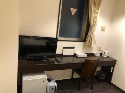 a desk in a room with a tv and a computer at Hotel Plaisir Tachikawa in Tachikawa