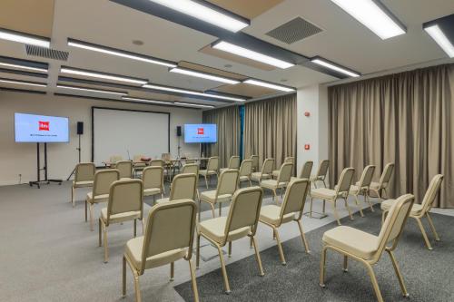 a conference room with chairs and a white screen at ibis Timisoara City Center in Timişoara