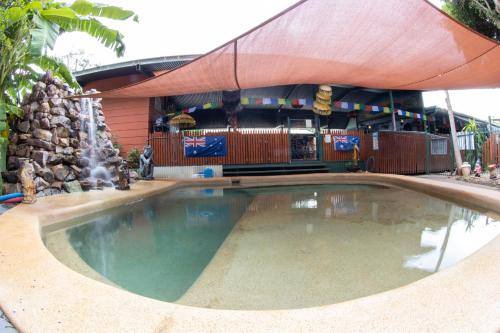 a swimming pool with a large umbrella on top of it at Batchelor Butterfly Farm in Batchelor