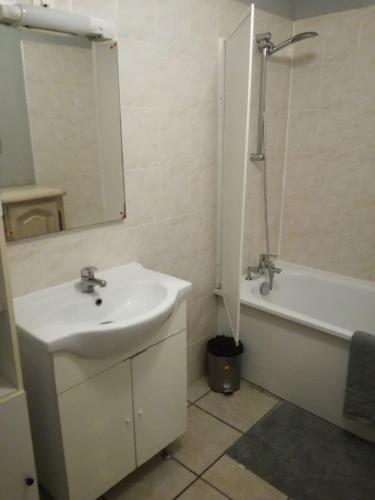 a bathroom with a sink and a tub and a mirror at Chambre d'Hôtes Spincourt 2 personnes in Spincourt