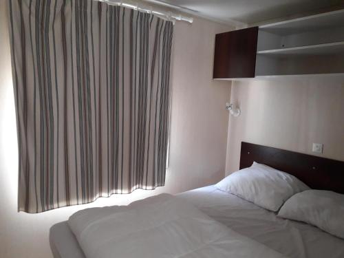 um quarto com uma cama branca e uma janela em mobil home em Lacanau-Océan
