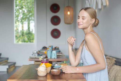 a woman is standing at a table with food at Amar Boutique Hotel in Canggu