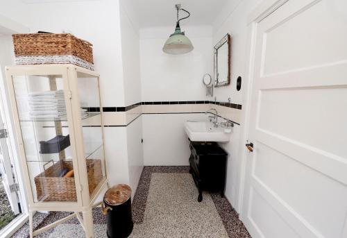 a white bathroom with a sink and a shelf at city-apartment een hele verdieping voor jezelf midden in het centrum in Apeldoorn