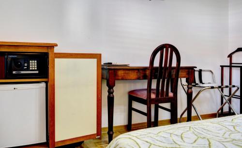a bedroom with a desk with a microwave and a chair at Villa Fortuna in Mostar