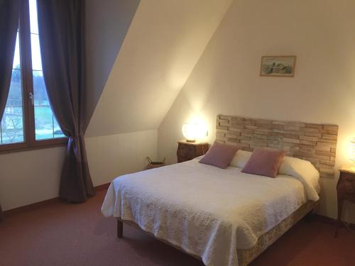 Souvigné的住宿－Le clos de Launay，一间卧室配有一张带两盏灯的床和一扇窗户。