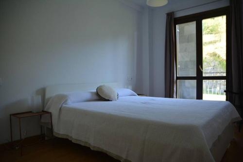ein weißes Bett in einem Zimmer mit Fenster in der Unterkunft Casa Miruetxe in Lekunberri