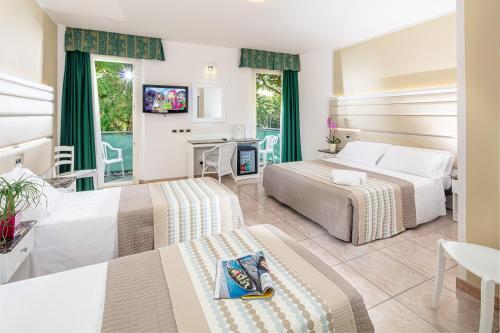 a hotel room with two beds and a tv at Hotel Mediterraneo in Lignano Sabbiadoro