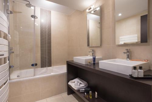 La salle de bains est pourvue d'un lavabo, d'une douche et d'une baignoire. dans l'établissement Hôtel Club MMV Les 2 Domaines, à Belle Plagne