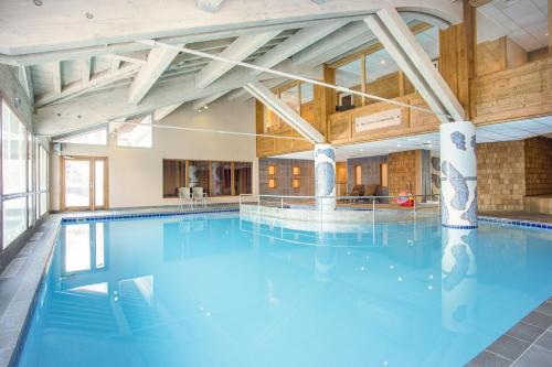 une grande piscine avec de l'eau bleue dans un immeuble dans l'établissement Hôtel Club MMV Les 2 Domaines, à Belle Plagne