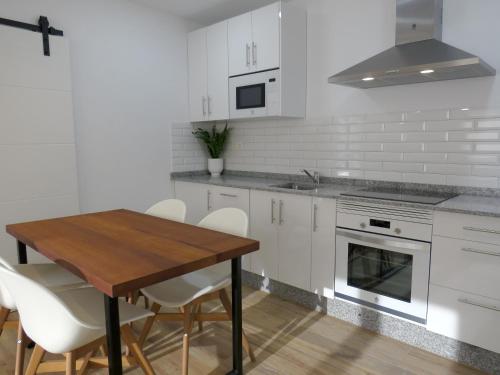 eine Küche mit einem Holztisch und weißen Schränken in der Unterkunft Apartamentos la Garita - Casa Juan yBlanca - Cudillero in Cudillero