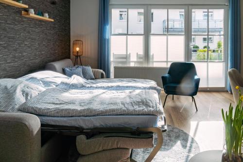 ein Schlafzimmer mit einem Bett, einem Stuhl und einem Fenster in der Unterkunft Fewo Seebrücke in Timmendorfer Strand
