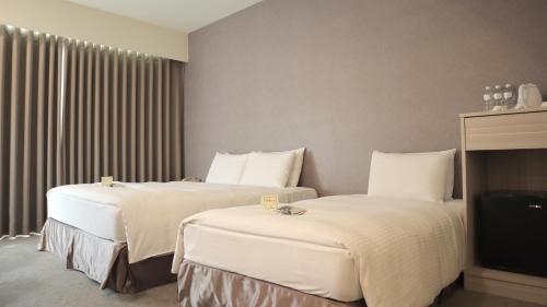 a hotel room with two beds and a television at Ho Fong Business Stay in Fengyuan