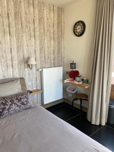 a bedroom with a bed and a desk and a clock at B&B 't Hoveke in Wingene