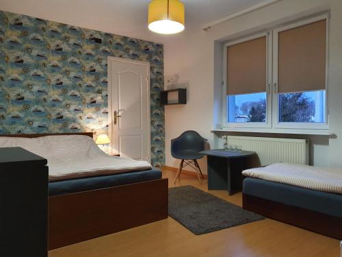1 dormitorio con cama, ventana y silla en Willa SOL en Mielno