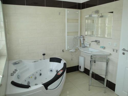 a white bathroom with a tub and a sink at Ostsee Strandvilla Silvia in Lobbe