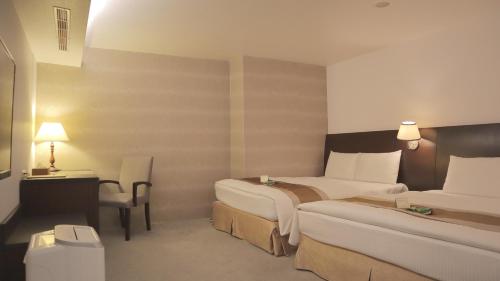 a hotel room with two beds and a desk at Ho Fong Business Stay in Fengyuan