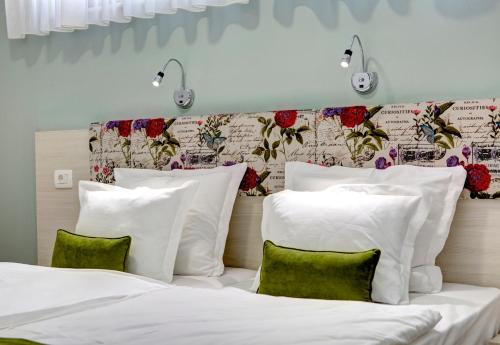 una camera con 2 letti con lenzuola bianche e cuscini verdi di Villa Fortuna a Mostar