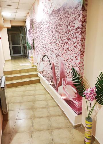 a hallway with a pink wall with pink flowers at Troyan Plaza Hotel in Troyan