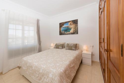 1 dormitorio con 1 cama y una pintura en la pared en El Gin, en Playa Blanca