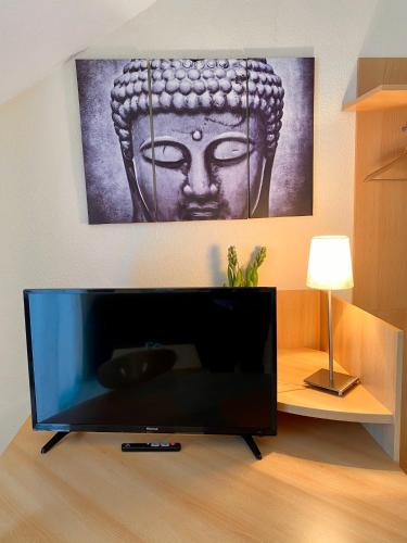a flat screen tv in a room with a picture of a head at Hotel Hilgers in Düren - Eifel