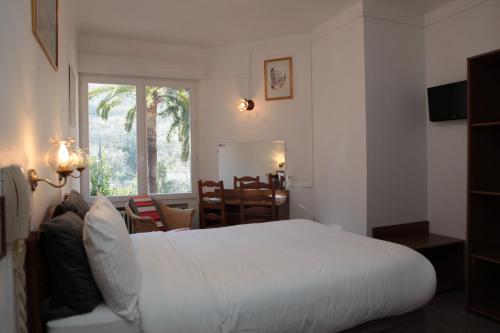 a bedroom with a white bed and a dining room at Auberge Les Gorges du Loup in Tourrettes-sur-Loup