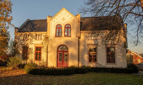 een groot wit huis met een rode deur bij Wiemannshof 25191 in Bunde