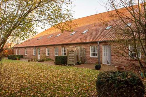 a red brick house with a red roof at Wiemannshof 25191 in Bunde