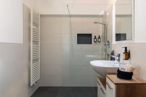 a white bathroom with a sink and a shower at Nina • Parchi e Fiume in Bressanone