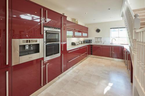 a large kitchen with red cabinets and a tile floor at Host & Stay - Folkton Cottages in Scarborough