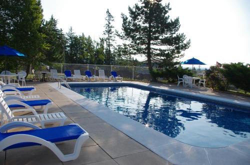 a swimming pool with chairs and tables and chairs at Silver Dart Lodge in Baddeck
