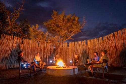 a group of people sitting around a fire pit at night at Sasi Africa Luxury Tented Bush Lodge in Bergville