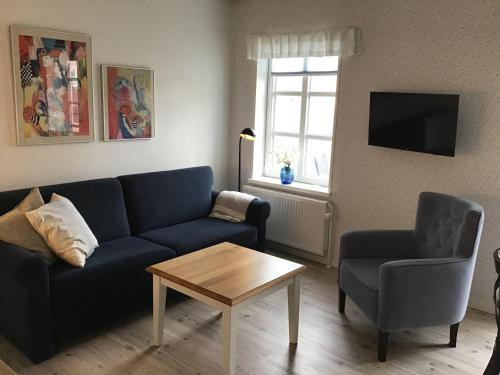 uma sala de estar com um sofá, uma mesa e uma cadeira em Løkken Badehotel Apartments em Lokken