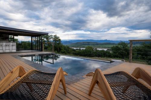 a swimming pool with two chairs on a wooden deck at Sasi Africa Luxury Tented Bush Lodge in Bergville