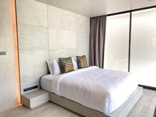 a bedroom with a large white bed and a window at Nirundorn Resort Chaam in Cha Am