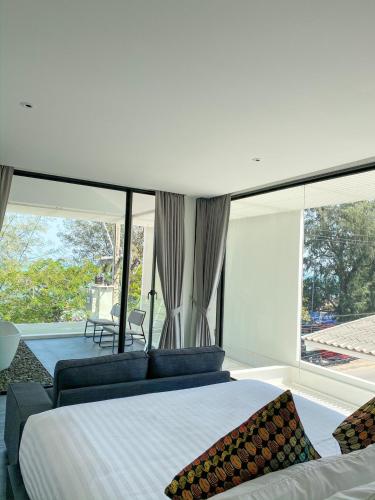 a bedroom with a large bed and large windows at Nirundorn Resort Chaam in Cha Am
