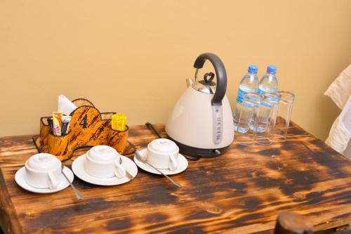 a wooden table with a tea kettle and plates and water bottles at Burka Coffee Lounge in Arusha