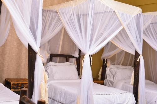 a bedroom with two beds with white drapes at Burka Coffee Lounge in Arusha