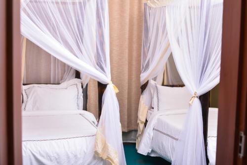 two beds with white curtains in a bedroom at Burka Coffee Lounge in Arusha