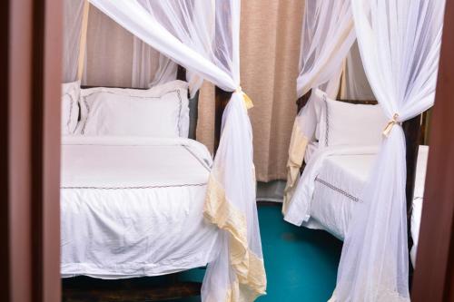 two beds in a room with white drapes at Burka Coffee Lounge in Arusha