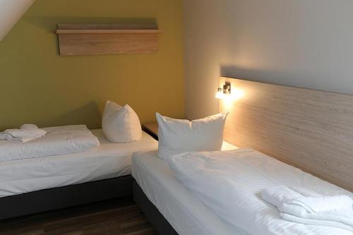 2 Betten in einem Hotelzimmer mit weißer Bettwäsche in der Unterkunft Der Westflügel Hofmaler WF-53 in Stolpe auf Usedom