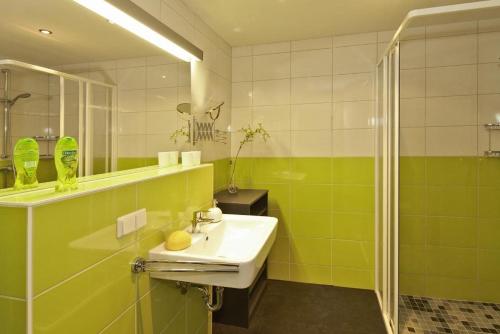 a green bathroom with a sink and a shower at Der Landhof Sanddorn in Stolpe