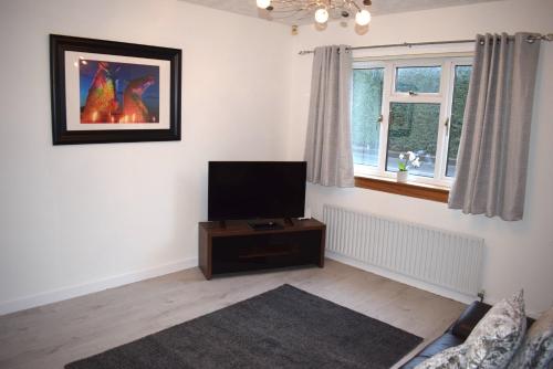 a living room with a flat screen tv on a table at Kelpies Serviced Apartments- Russell in Falkirk