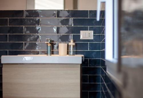a bathroom with a sink and a blue tiled wall at Case Playa Resort Balestrate in Balestrate